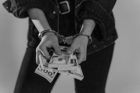 criminal in handcuffs with cash money